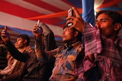 Young Indian men film on their mobile phones girls dancing on the stage inside on of the theatres at Sonepur Mela